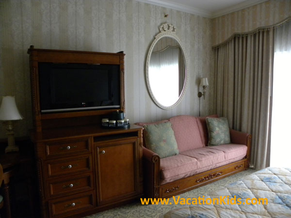 Flat screen TV and mini fridge with Victorian furniture blend into comfortable surroundings for your family at the Grand Floridian