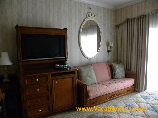 Flat screen TV and mini fridge with Victorian furniture blend into comfortable surroundings for your family at the Grand Floridian