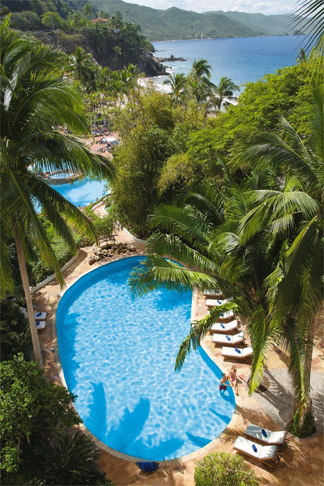 View of adult pool amidst palms and mountains at Dreams Puerto Vallarta Resort & Spa