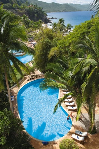 View of adult pool amidst palms and mountains at Dreams Puerto Vallarta Resort & Spa